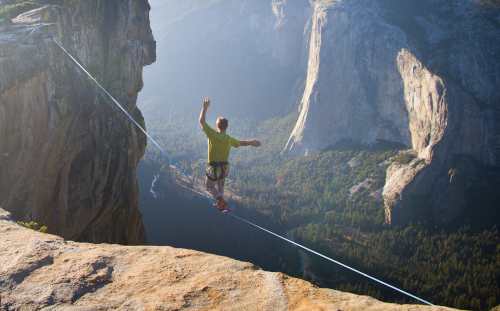 photo of a man slacklining above Yosemite Valley